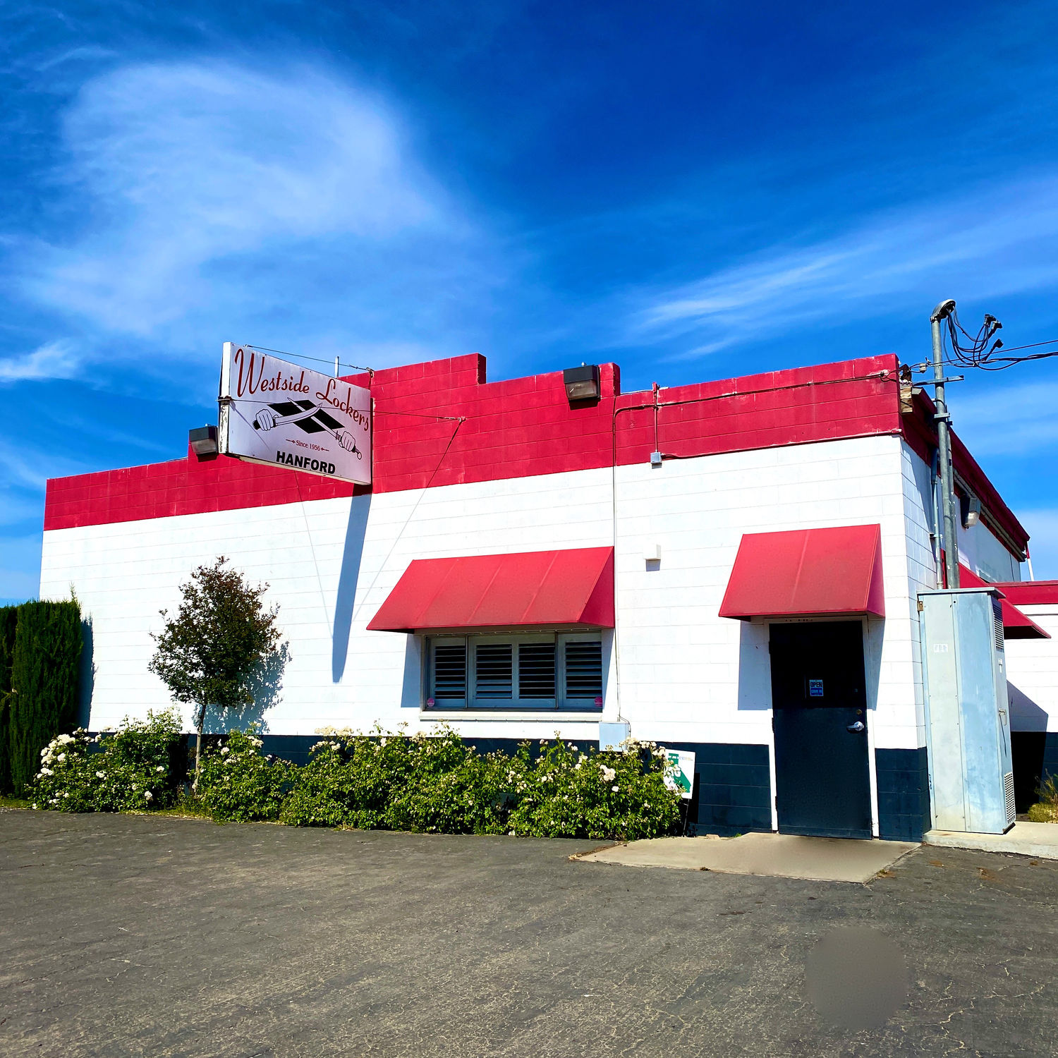 The Westside Lockers shop in Hanford — a red-and-white building under a clear sky, with a hanging sign reading Westside Lockers, Since 1956, Hanford.
